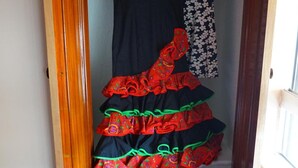 A closet with hanging dresses and a red suitcase. - Hostal Alamare (Seville)