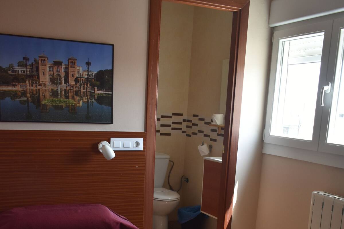 Hotellihuone, jossa on kaksi sänkyä, kylpyhuone, ikkuna ja taulu seinällä.