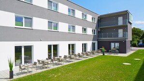 Un edificio moderno con varios balcones y un patio con mobiliario exterior.