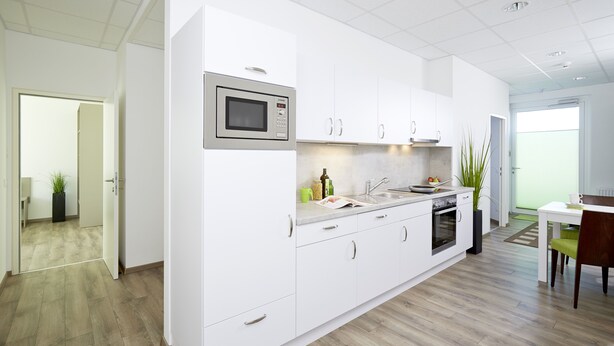 Una cocina moderna con armarios blancos, microondas integrado y un comedor con mesa y sillas.