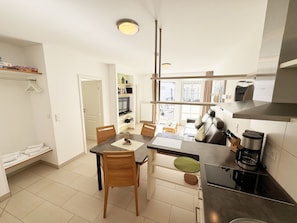 A modern kitchen with a dining area, a built-in oven, and a coffee maker.