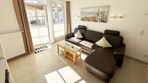 A modern living room with a sofa, a coffee table, and a painting on the wall. - F: House Meeresblick A 2.11 Sun deck with balcony - House Meeresblick A 2.11 (Baabe)