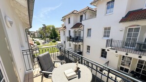 A balcony with a round table and two chairs, overlooking a residential area with multiple buildings. - F: House Meeresblick A 2.11 Sun deck with balcony - House Meeresblick A 2.11 (Baabe)