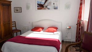 A bedroom with a bed, a wooden wardrobe, a chair, a bedside table, and a painting on the wall. - Beachside 3-Star Apartment with WIFI and Parking, 20m from the Shore in Trégastel (Trégastel)