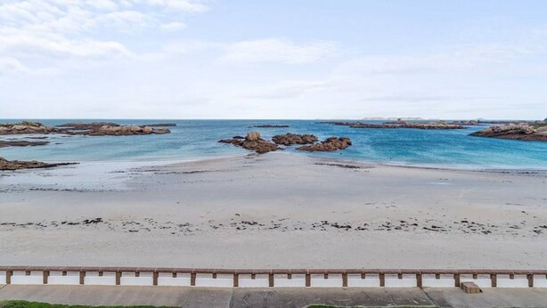 A beach with a clear sky, rocky formations in the water, and a sandy shore. - Beachside 3-Star Apartment with WIFI and Parking, 20m from the Shore in Trégastel (Trégastel)