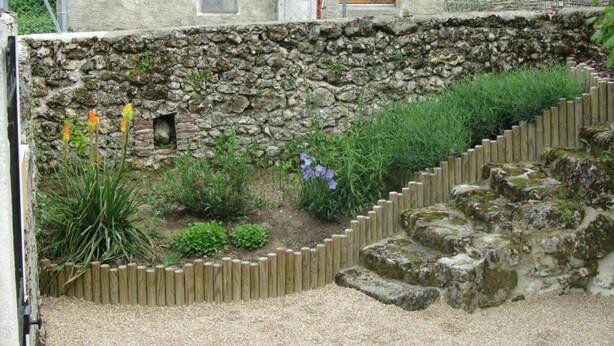 A garden with a stone wall, wooden steps, and various plants. - Charming house near Tours, enclosed garden, perfect for families (Montlouis-sur-Loire)