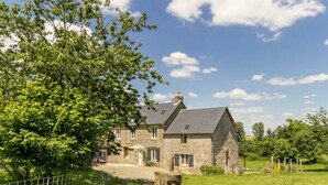 A stone house with a paved driveway and a fenced yard. - Charming Normandy cottage with wood stove and private yard (Bourguenolles)