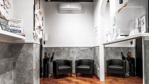 Un interior moderno con suelo de madera en espiga, dos sillones de cuero negro, una pared de mármol y un aire acondicionado instalado.