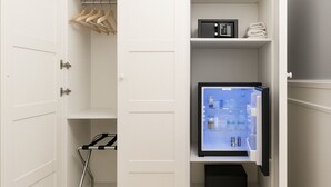 Una habitación compacta con un mini refrigerador incorporado, un estante pequeño con toallas y un perchero metálico.