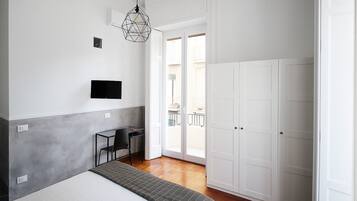 A bedroom with a bed, a desk, a chair, a TV, and a wardrobe.