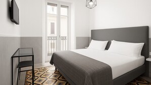 Un dormitorio moderno con cama, mesita de noche, televisor montado en la pared y suelo con estampado geométrico.