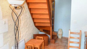 Un escalier en bois mène à une mezzanine dotée d’un plafond en pente, d’un lampadaire et d’une petite table avec des chaises.