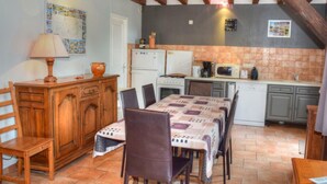 Une cuisine rustique avec une table à manger, des chaises, des meubles en bois et un sol carrelé.