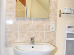Une salle de bain avec un lavabo, un miroir et des murs carrelés.