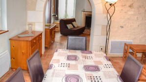 Un coin repas accueillant avec une table dressée pour quatre personnes, un fauteuil marron et un meuble en bois.