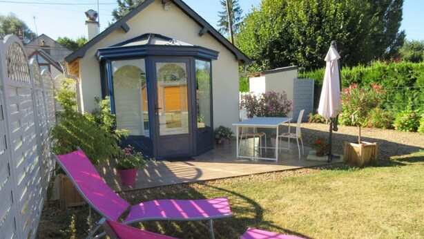 Eine Terrasse mit Tisch und Stühlen, ein Pavillon und ein eingezäunter Gartenbereich.
