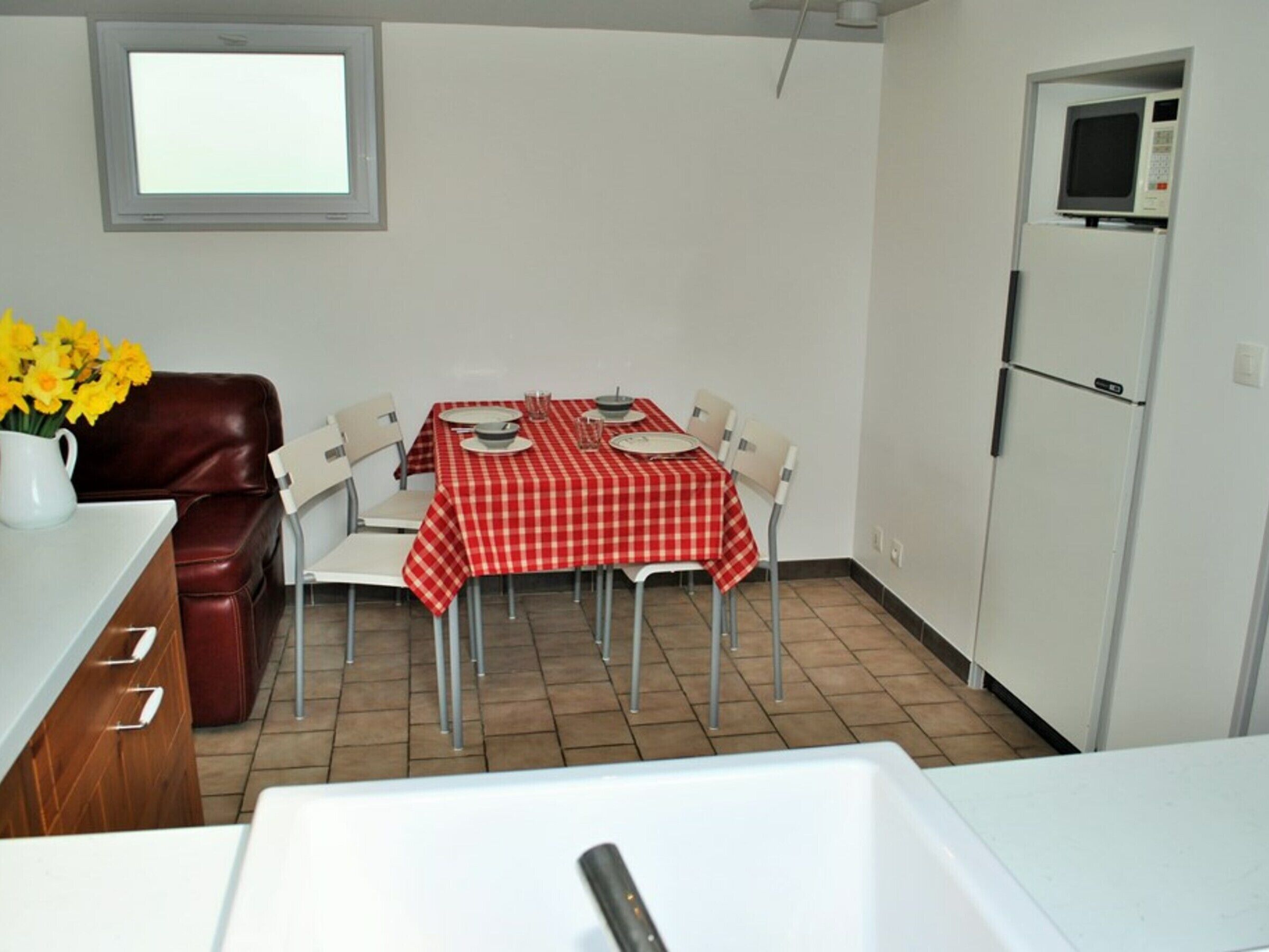 Una cocina compacta con una mesa de comedor preparada para dos personas, un refrigerador y un microondas.