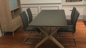 Un comedor con una mesa rectangular, seis sillas, un aparador de madera y una ventana con cortina.