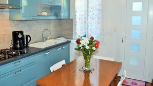 A kitchen with blue cabinets, a coffee maker, and a vase with flowers on the table.