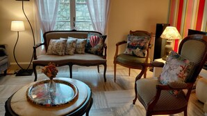 Ein gemütliches Wohnzimmer mit einer Couch, Sesseln, einem Couchtisch und einer Lampe.