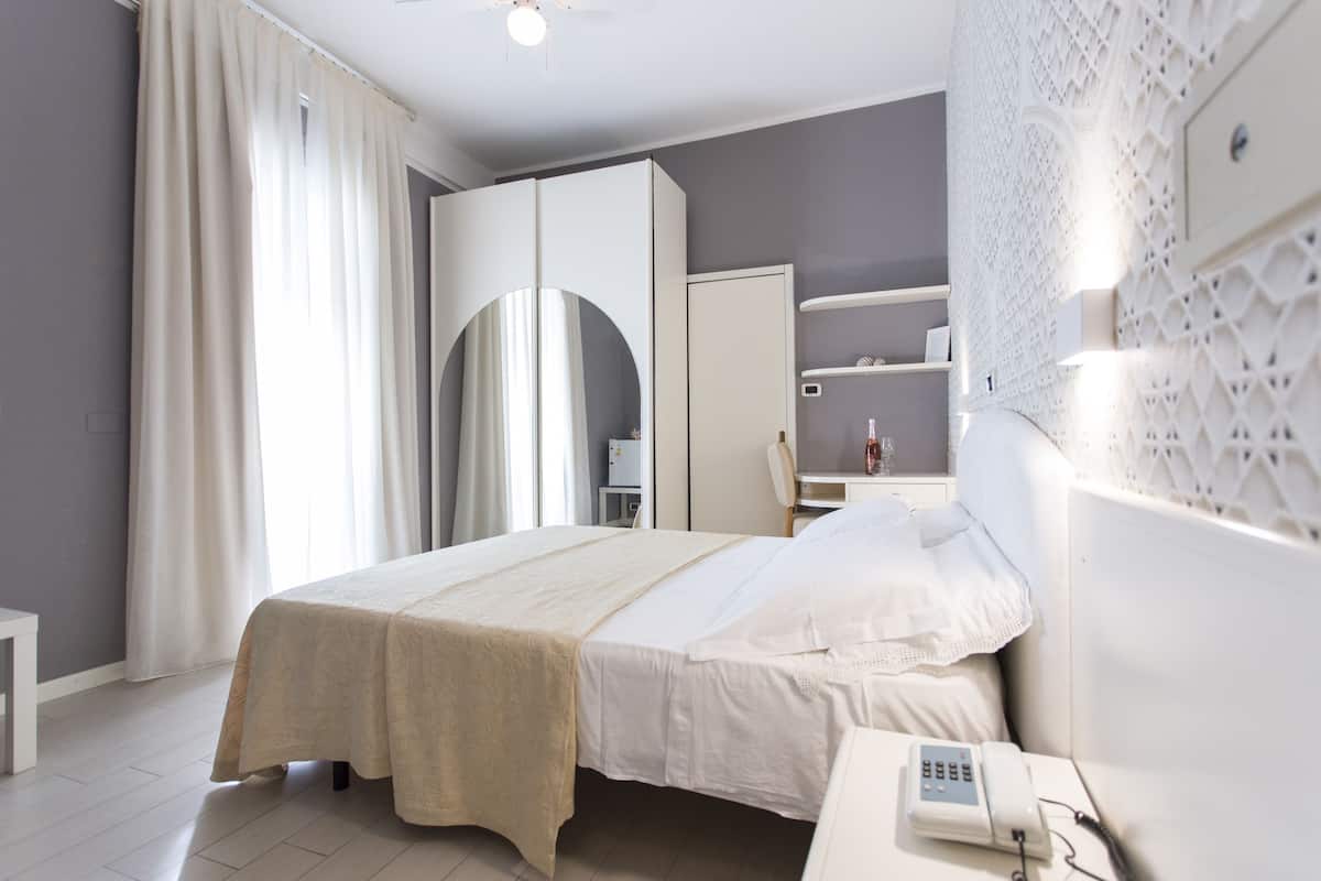 Une chambre d’hôtel moderne équipée d’un lit, d’une table de chevet et d’un bureau avec une chaise.