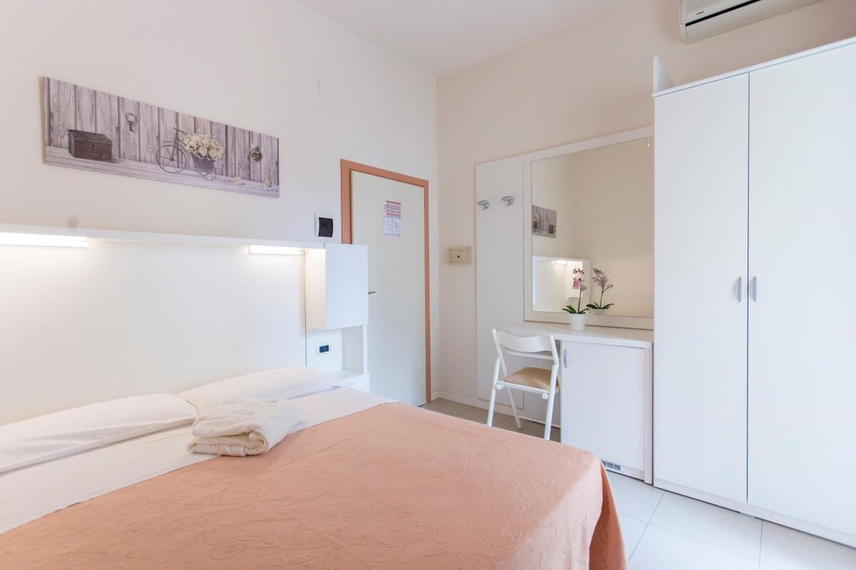 Une chambre à coucher avec un lit, un bureau, une chaise et une armoire.