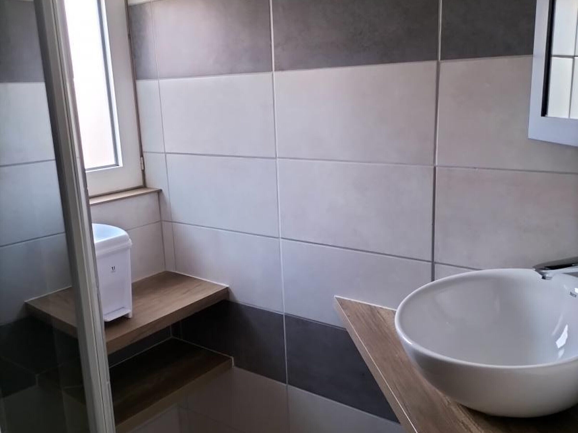 Een badkamer met een wit wastafel, toilet en raam.