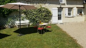 A stone house with a tiled roof, a white door, and a small balcony. - Charming Tufa Stone Cottage with Courtyard, Near Loire Castles, Electric Bike Rental Available (Savigny-en-Véron)