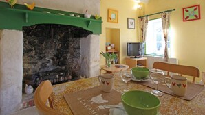 Un accogliente soggiorno con camino, televisione e zona pranzo con tavolo apparecchiato per due.