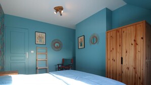 Una camera da letto con un letto, un'armadietto in legno, una scala e due sedie.