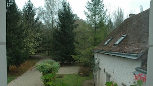 A house with a gravel path leading to a garden, surrounded by trees. - Charming Getaway for Two: Historic Farm, Private Garden, Bikes & Ping-Pong Included (Souvigny-de-Touraine)