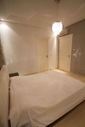 A bedroom with a large bed, two doors, and a chandelier.