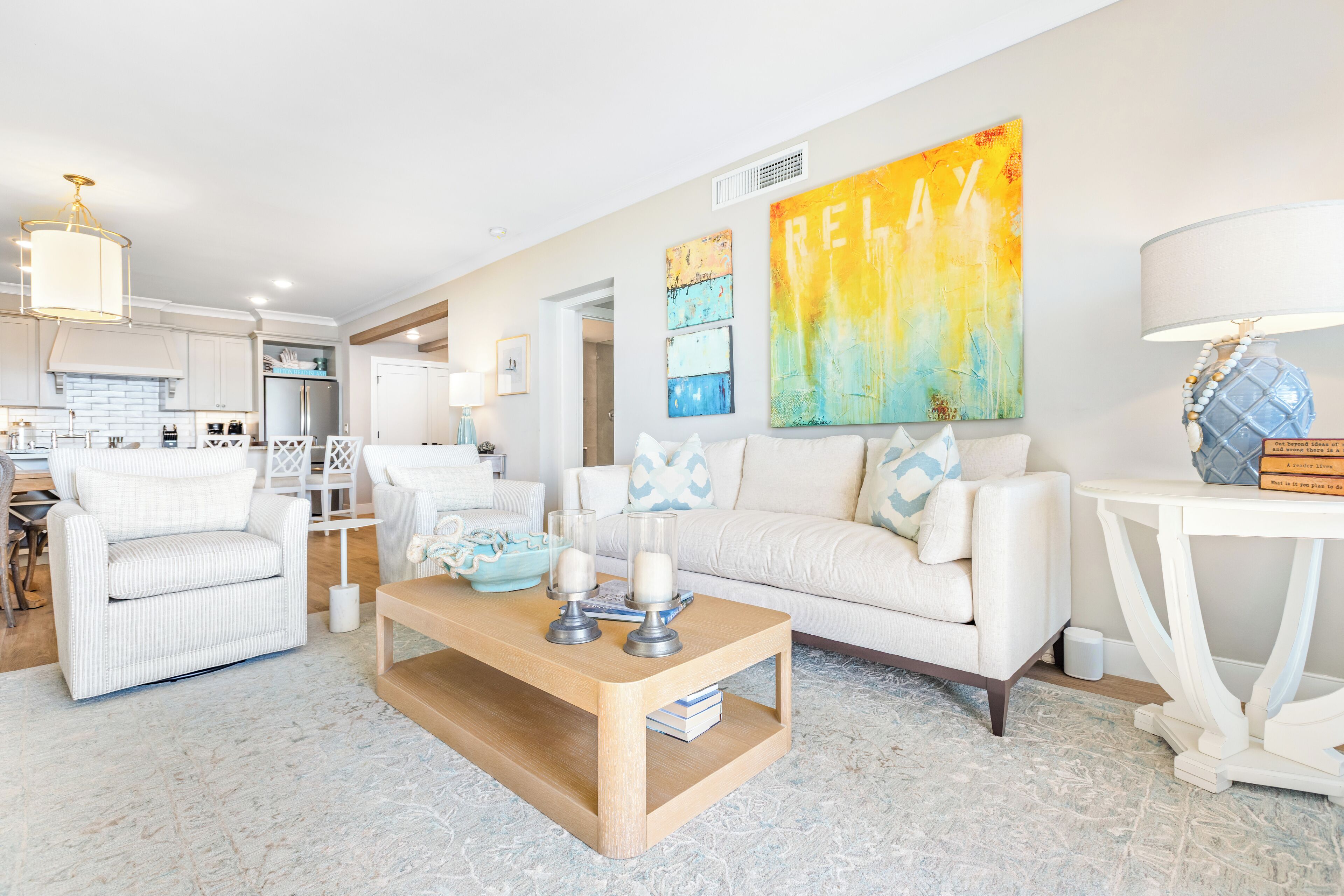 A modern living room with a white sofa, a wooden coffee table, and a colorful abstract painting on the wall.