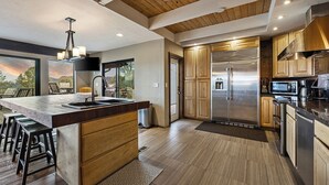 Una cocina moderna con una isla grande, electrodomésticos de acero inoxidable y vistas al exterior.