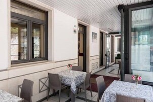 Un área de comedor al aire libre con mesas y sillas, un letrero de bar y una ventana con vistas.