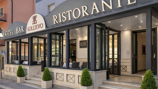 A hotel bar with a modern facade, large windows, and outdoor seating. - Hotel Sollievo (San Giovanni Rotondo)