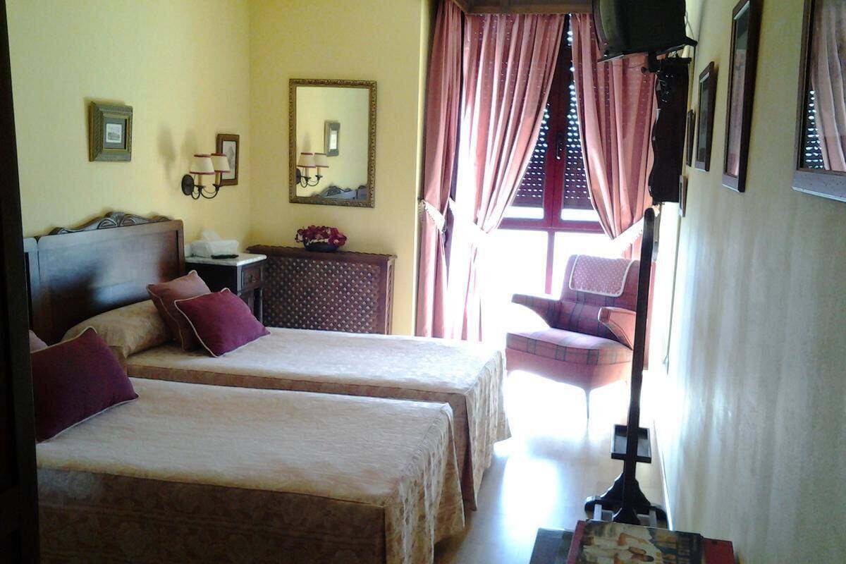 A hotel room with two beds, a dresser, a mirror, and a window with curtains.