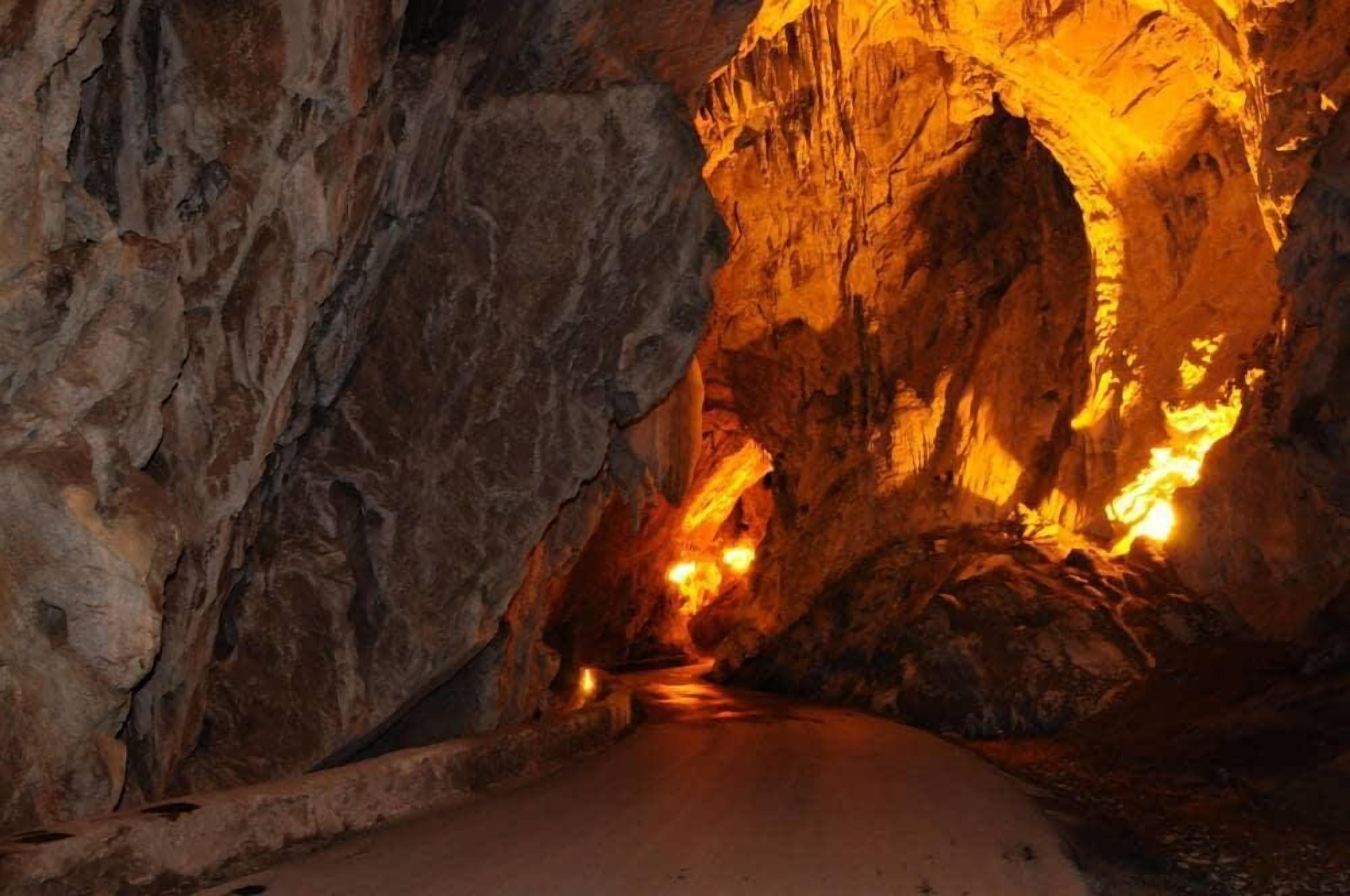Un estrecho pasaje con paredes rocosas y una cálida luz brillante al final.