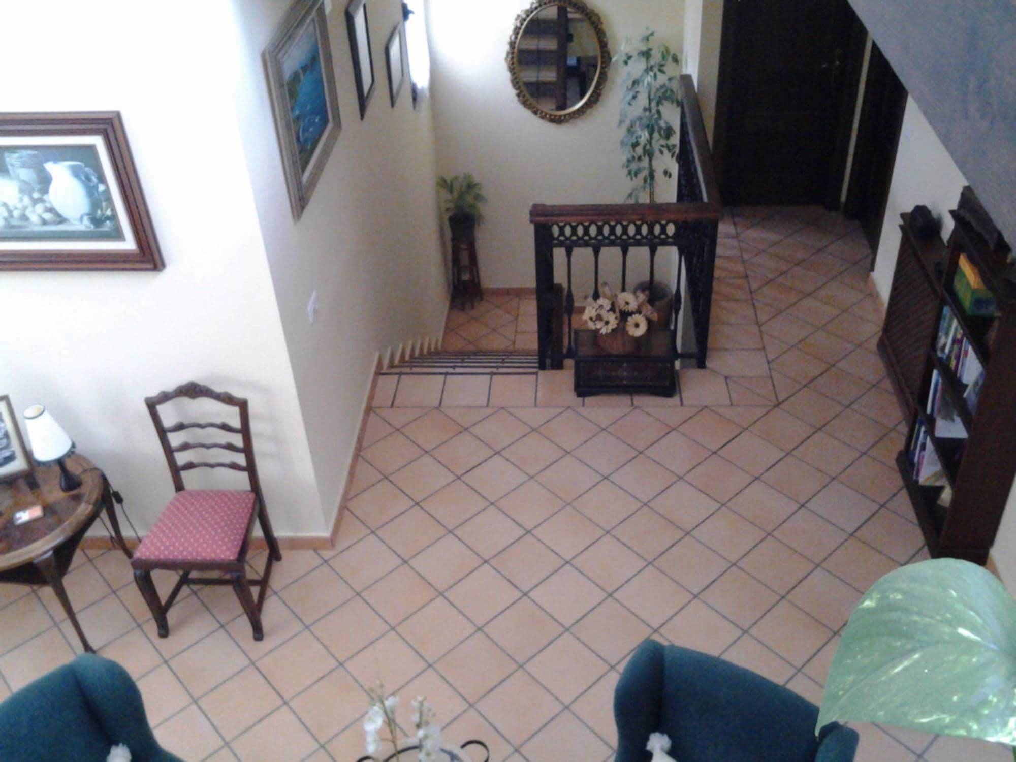 Ein Wohnzimmer mit Fliesenboden, einer Holzbank, einem Sessel und einem Bücherregal.