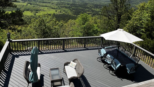 Una terraza con mobiliario exterior, incluyendo sillas y una mesa, con vistas a un paisaje pintoresco.