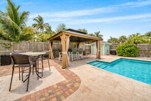 Un jardin avec une piscine, des meubles de patio et une pergola en bois.