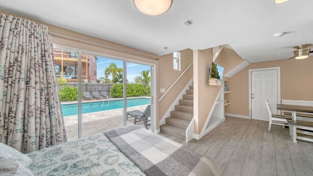 Une chambre avec une grande fenêtre, un escalier, une vue sur la piscine et un plancher en bois.