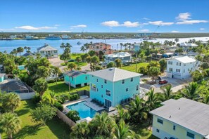 A residential area with houses, a swimming pool, and a marina in the background.