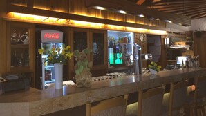A bar area with wooden beams, a Coca-Cola refrigerator, a coffee machine, and a teddy bear decoration. - Abels Appartements (Bochum)