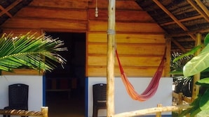 A wooden structure with a thatched roof, a hammock, and a small porch area. - Safasurf Camp - Hostel (Arugam Bay)
