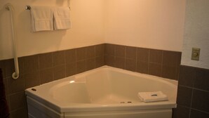 A bathroom with a white bathtub, a towel rack with two towels, and brown tiled walls. - Odisha House of Rest (Shawano)