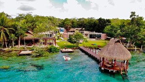 Un resort tropical con una laguna azul cristalina, bungalows sobre el agua y una estructura con techo de paja.