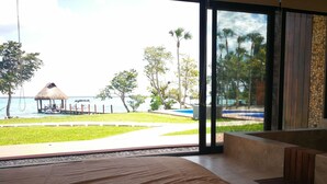 Una habitación con un ventanal grande que da a una piscina y una playa.