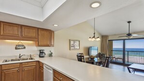 A kitchen with wooden cabinets, a dishwasher, and a dining area with a view of the ocean. - 314- BEACH FRONT, gulf view, family-friendly! Destin Beach Club (Destin)