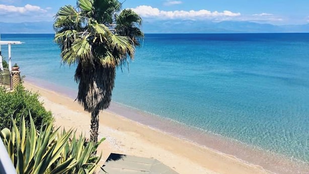 A beach with clear blue water, a palm tree, and a clear sky. - Panorama beach (Chrani)